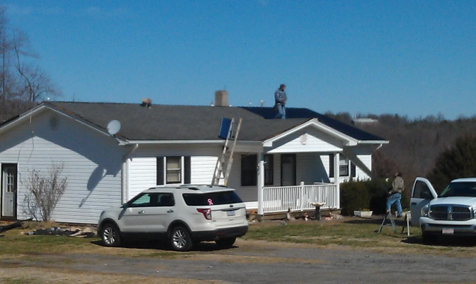 Roofers stripping shingles from a white ranch house roof in Lafayette